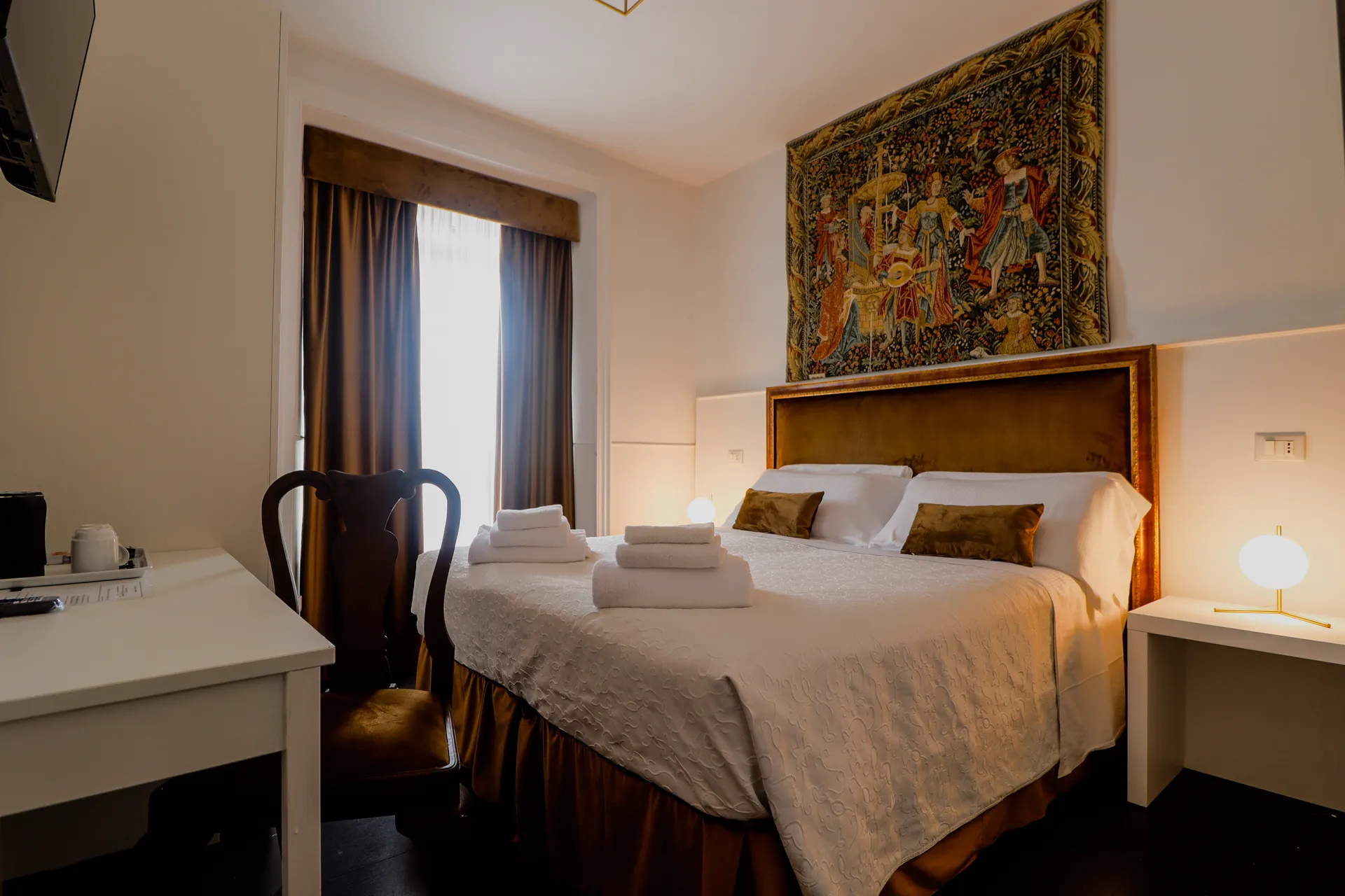 Suite di Imperial Suite Rome: testiera dorata, arazzo antico e scrivania accanto alla finestra