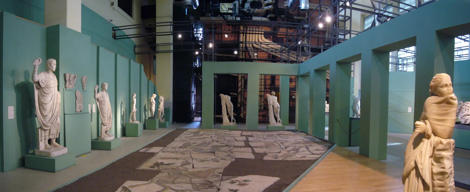 La sala caldaie della Centrale Montemartini a Roma: statue classiche in marmo bianco esposte tra i macchinari neri della vecchia centrale termoelettrica