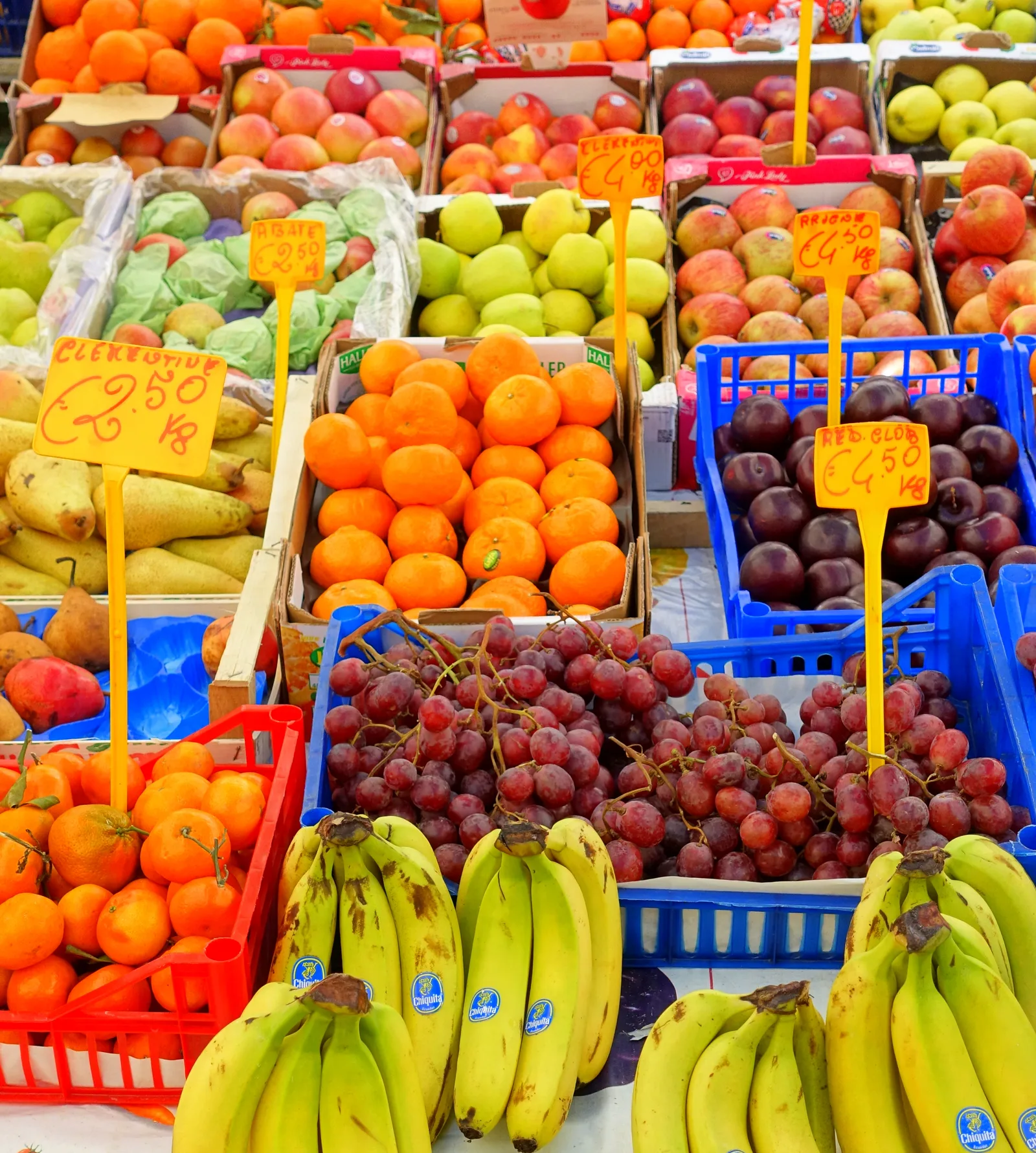 Banco di frutta e verdura al mercato di Campo de' Fiori a Roma: cassette di pomodori, zucchine e ortaggi di stagione esposti sotto i teli del mercato all'aperto