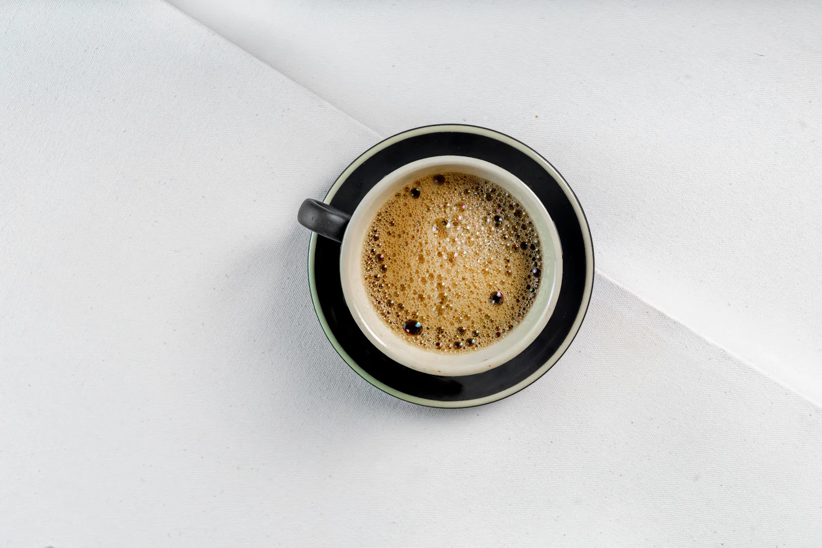 Tazzina di espresso al banco con la crema nocciola in superficie, il caffè bevuto in piedi al bancone come usano i romani