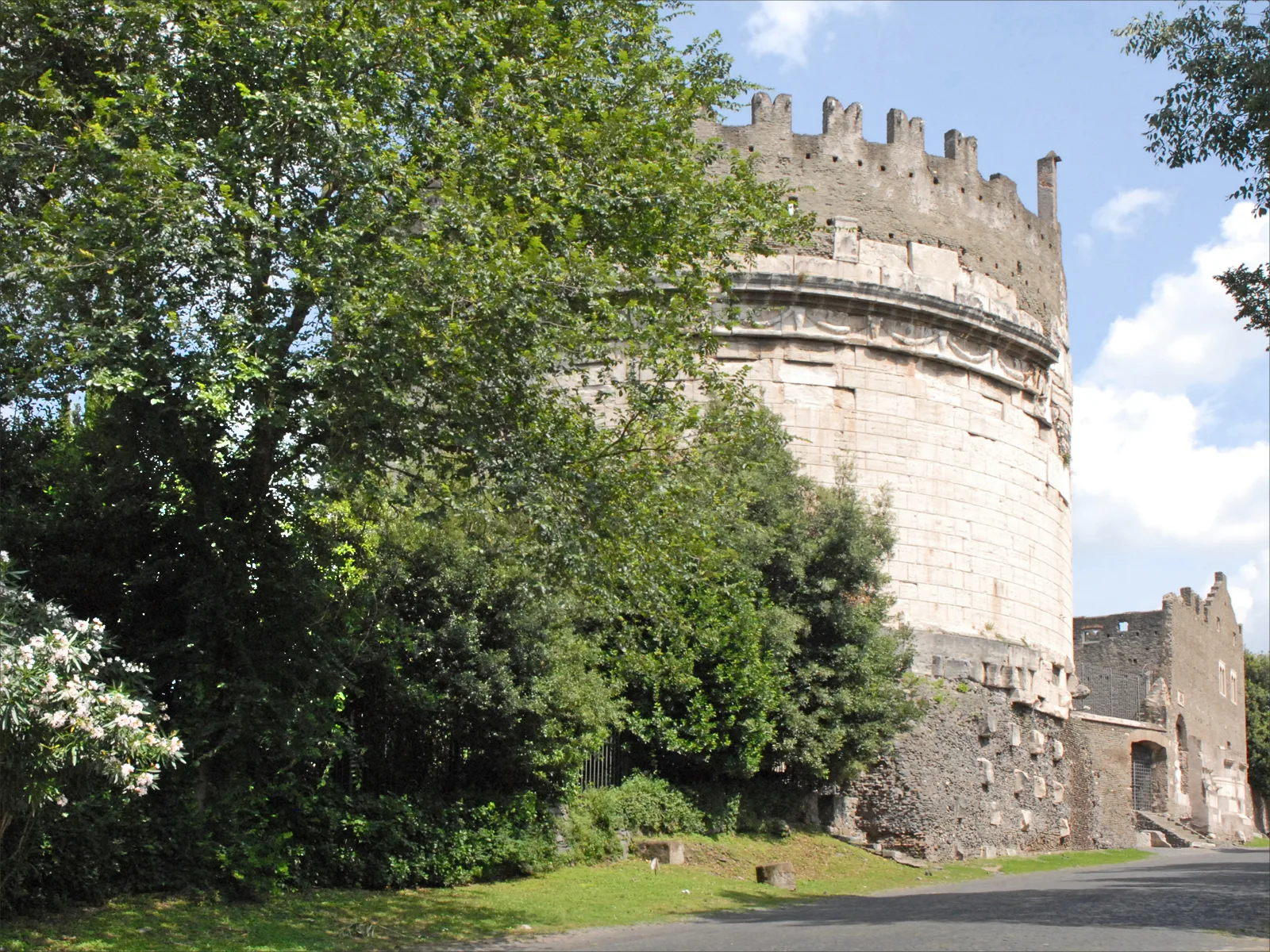 Tratto del basolato originale della Via Appia Antica a Roma: grandi lastre di basalto consumate dal tempo, fiancheggiate da pini e resti di sepolcri