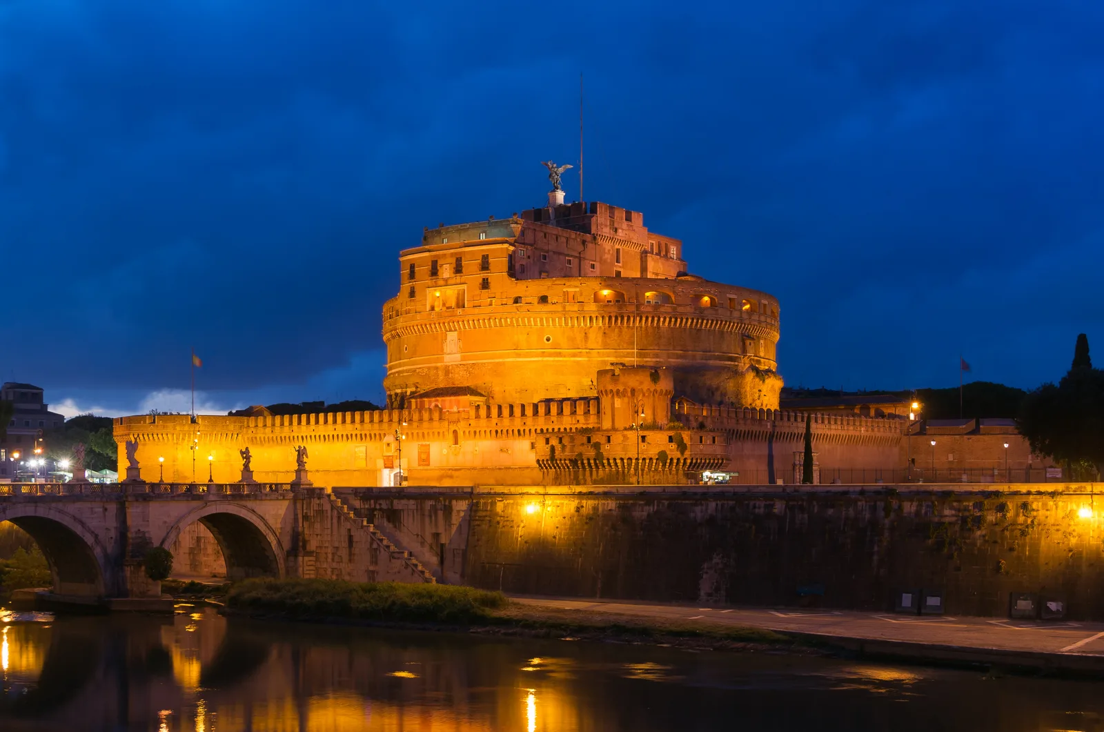 Ponte Sant'Angelo e Castel Sant'Angelo a Roma all'imbrunire, con le statue degli angeli sul ponte e il cielo che vira al blu sopra il Tevere