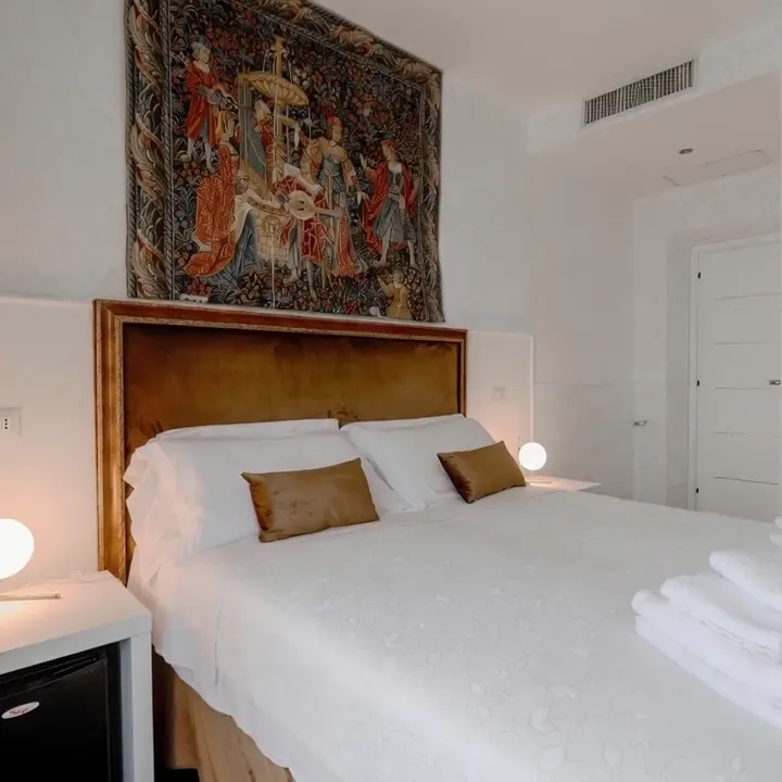 Suite di Imperial Suite Rome: testiera dorata, arazzo antico e scrivania accanto alla finestra